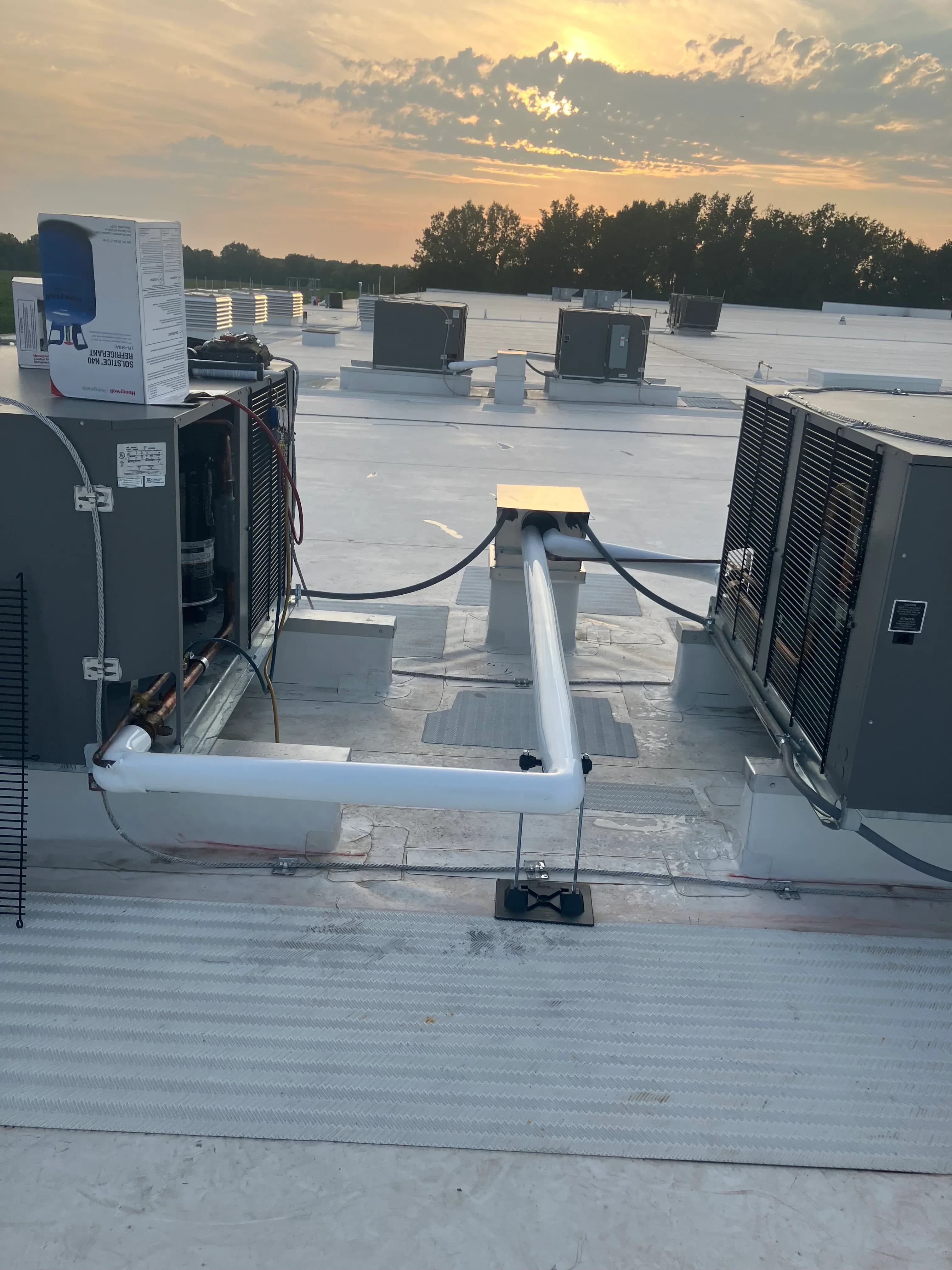 Rooftop condensing units opened up for an after-hours repair at dusk