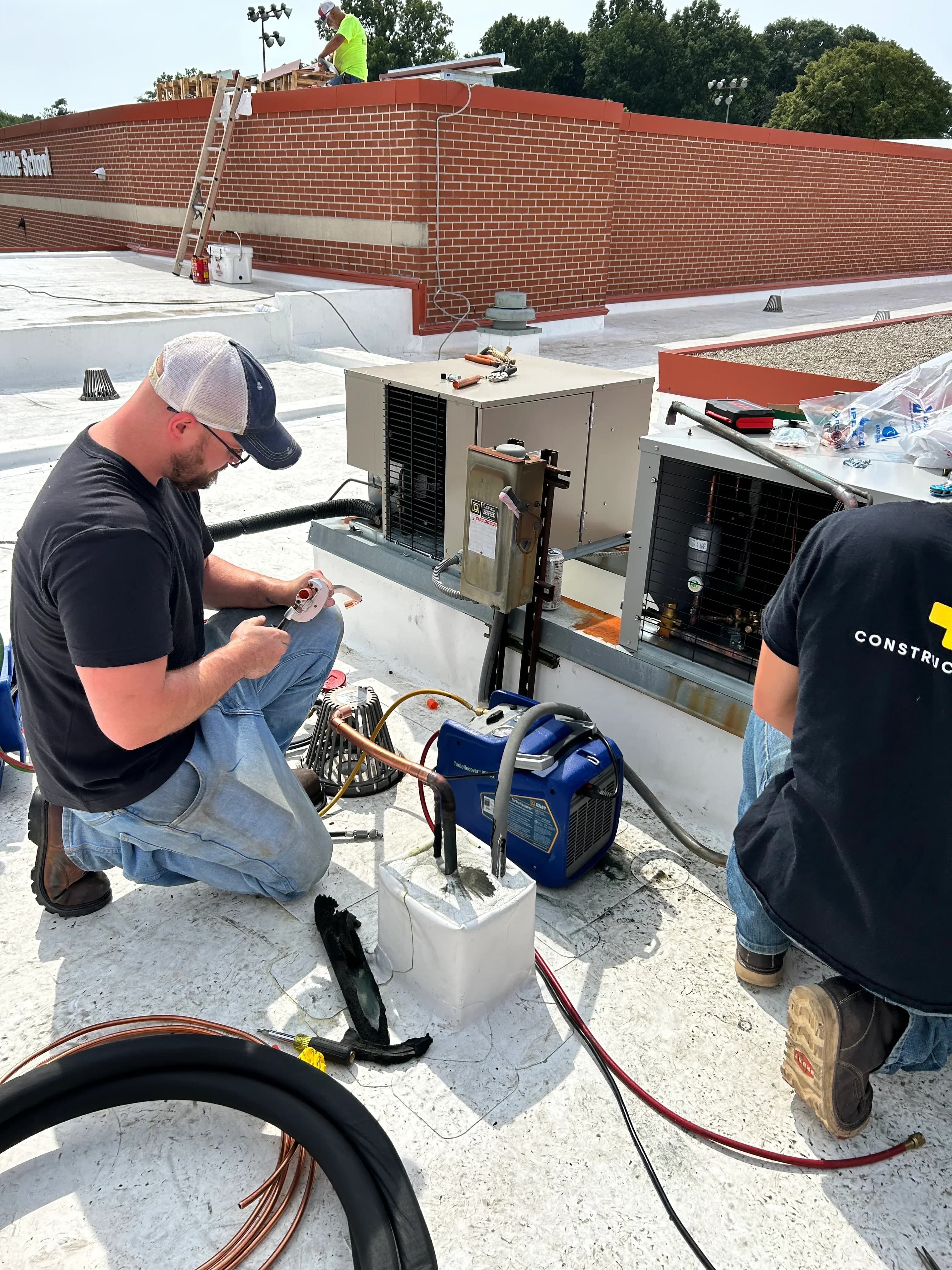 Two technicians collaborating on a rooftop refrigeration repair