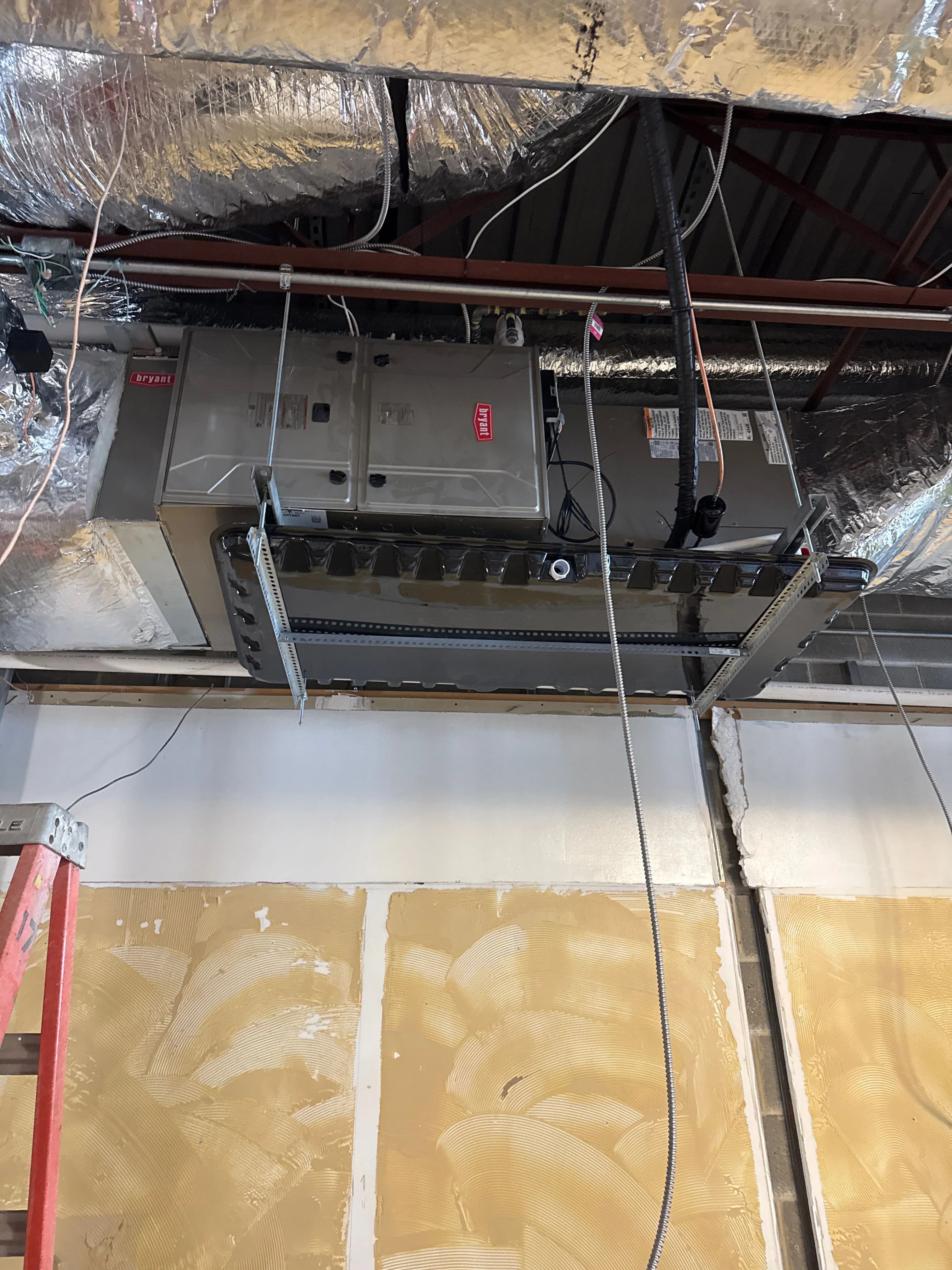 A suspended commercial air handler being repaired above the ceiling