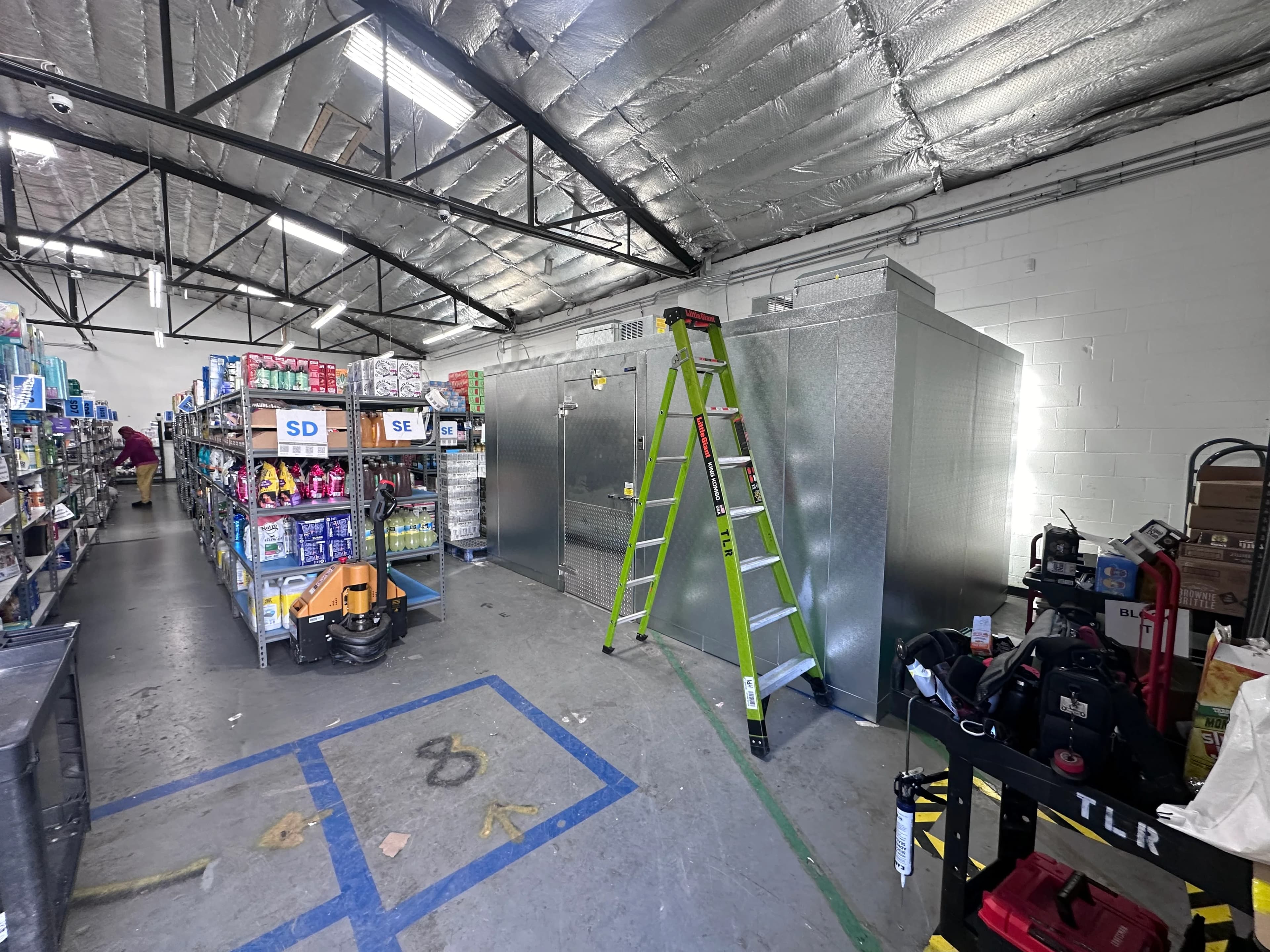 A walk-in cooler being installed in a convenience store back room
